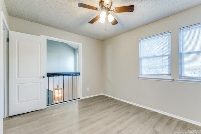 empty room featuring ceiling fan, light hardwood / wood-style flooring, and a textured ceiling