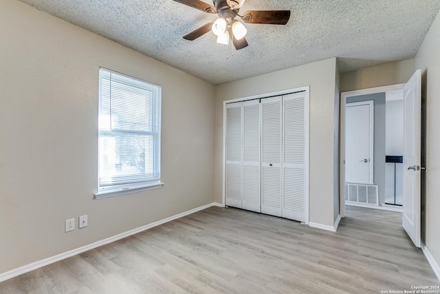 unfurnished bedroom featuring ceiling fan, light hardwood / wood-style floors, a textured ceiling, and a closet