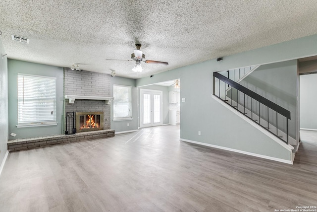 unfurnished living room with a fireplace, a textured ceiling, hardwood / wood-style flooring, and plenty of natural light