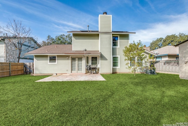 back of property with french doors, a patio, and a lawn