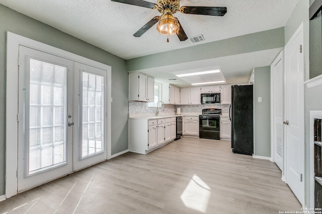 kitchen with black appliances, plenty of natural light, white cabinets, and light hardwood / wood-style flooring