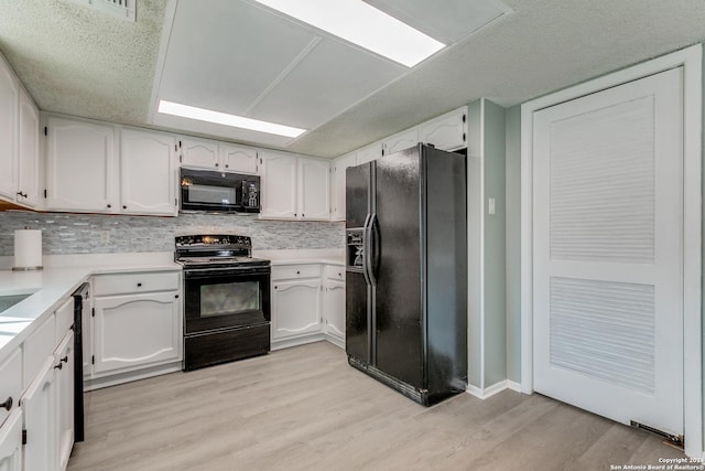 kitchen featuring black appliances, light wood-type flooring, white cabinetry, and backsplash