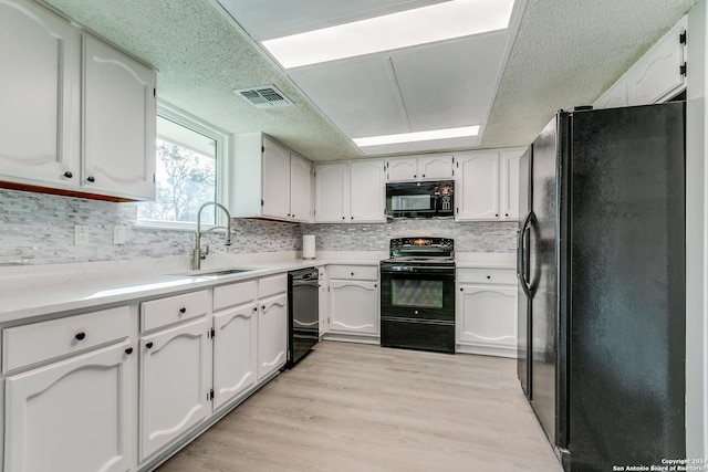 kitchen featuring white cabinetry, sink, a textured ceiling, black appliances, and light wood-type flooring