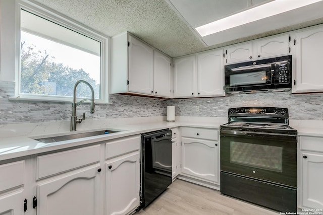 kitchen featuring white cabinetry, sink, tasteful backsplash, light hardwood / wood-style flooring, and black appliances