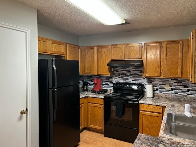 kitchen featuring decorative backsplash, sink, black appliances, and light hardwood / wood-style floors