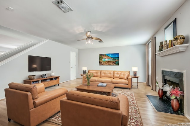 living room featuring ceiling fan, a fireplace, and light hardwood / wood-style flooring