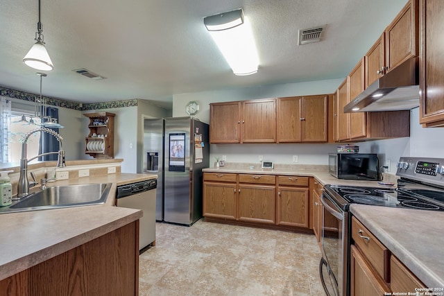 kitchen featuring appliances with stainless steel finishes, sink, pendant lighting, and a textured ceiling