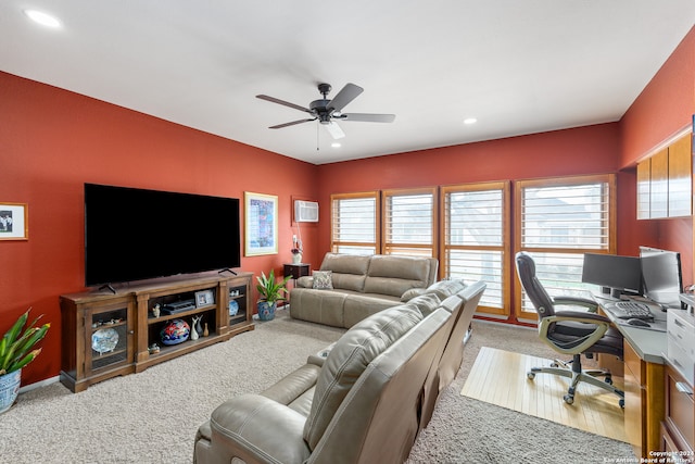 carpeted living room with ceiling fan and a wall mounted air conditioner