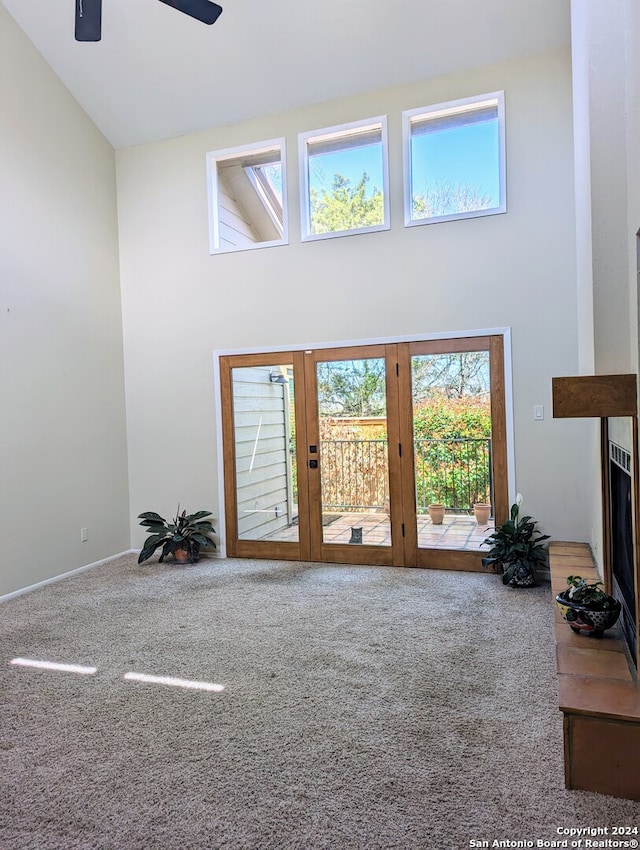 carpeted living room with ceiling fan and high vaulted ceiling