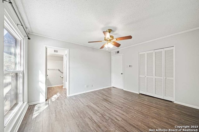 unfurnished bedroom featuring ceiling fan, crown molding, dark wood-type flooring, and a textured ceiling