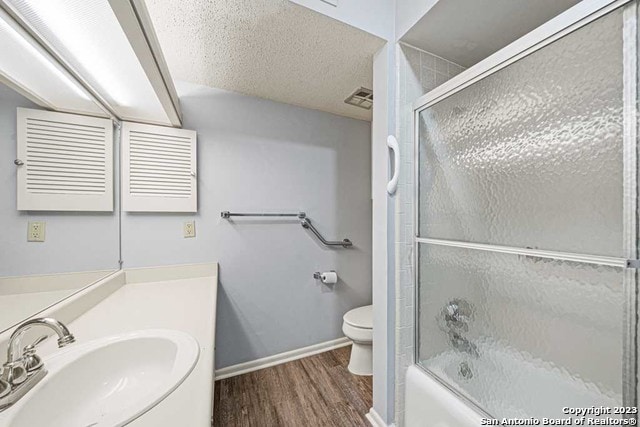 full bathroom with enclosed tub / shower combo, a textured ceiling, toilet, vanity, and hardwood / wood-style flooring