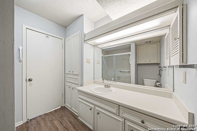 bathroom with toilet, vanity, a textured ceiling, and hardwood / wood-style flooring