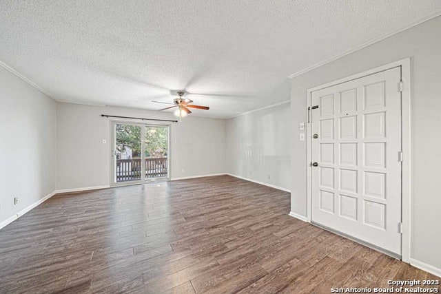 spare room with ceiling fan, dark wood-type flooring, a textured ceiling, and ornamental molding