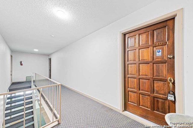 hallway featuring a textured ceiling and carpet floors