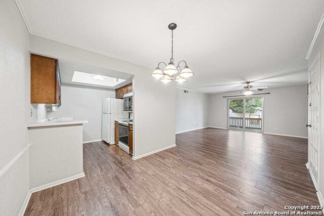 interior space featuring a skylight, crown molding, a textured ceiling, ceiling fan with notable chandelier, and hardwood / wood-style flooring