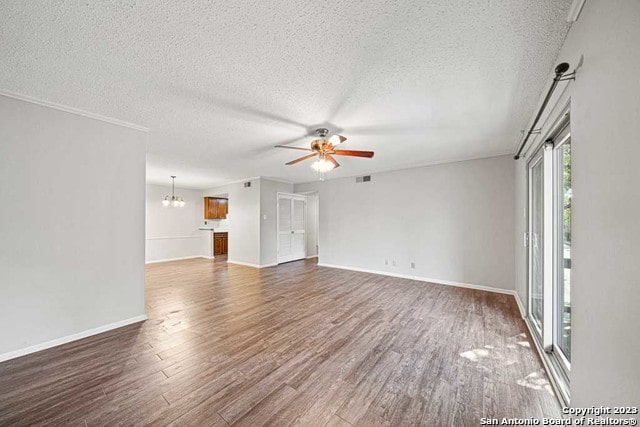 unfurnished living room featuring ceiling fan with notable chandelier, a textured ceiling, and dark hardwood / wood-style flooring