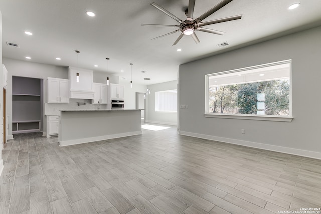 unfurnished living room featuring ceiling fan, sink, and light hardwood / wood-style flooring