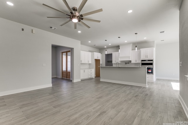 unfurnished living room with light wood-type flooring, ceiling fan, and sink