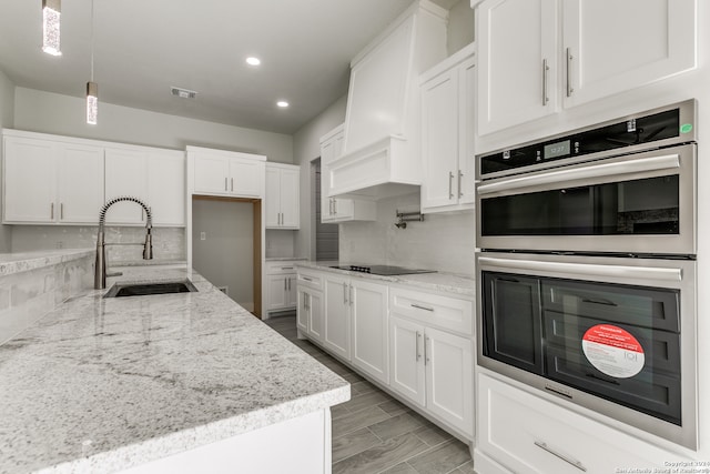 kitchen featuring white cabinets, sink, black electric cooktop, double oven, and light stone counters