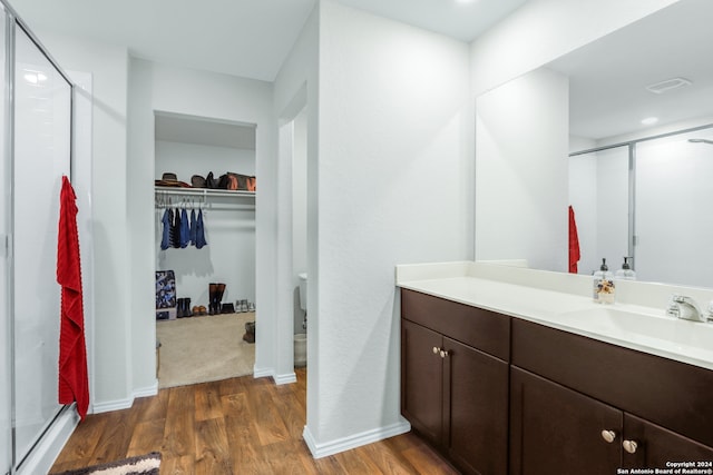 bathroom with hardwood / wood-style floors, vanity, and a shower with door