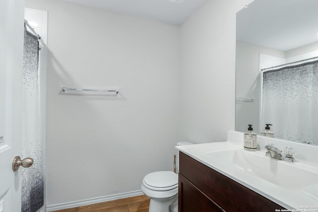 bathroom with hardwood / wood-style floors, vanity, toilet, and walk in shower