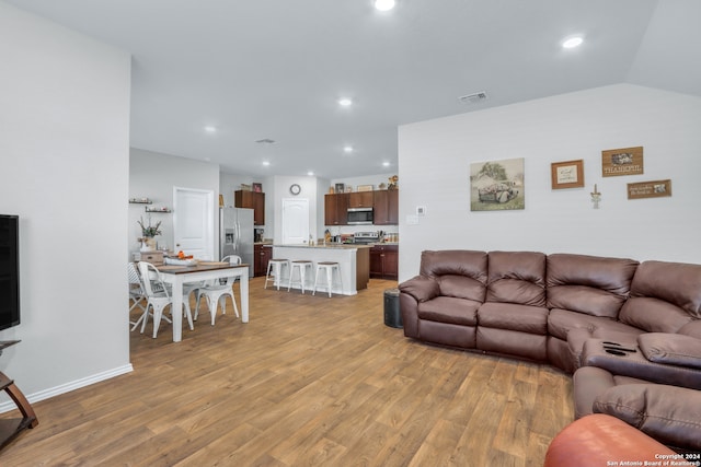 living room with light wood-type flooring and vaulted ceiling