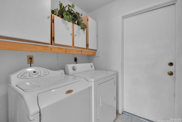 laundry area featuring washer and clothes dryer, cabinets, and a textured ceiling