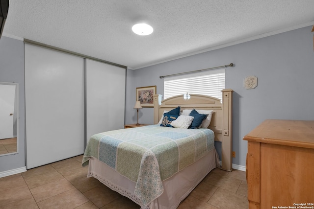 bedroom with light tile patterned flooring, a textured ceiling, and ornamental molding