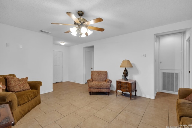 living room featuring ceiling fan, light tile patterned floors, and a textured ceiling