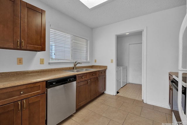 kitchen with dishwasher, sink, separate washer and dryer, a textured ceiling, and light tile patterned flooring