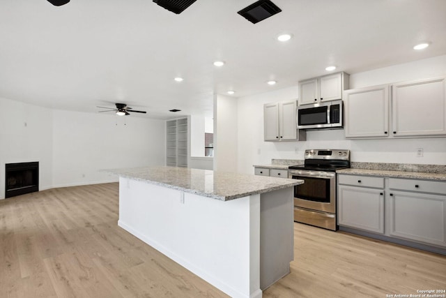 kitchen featuring ceiling fan, a kitchen island, stainless steel appliances, and light hardwood / wood-style floors