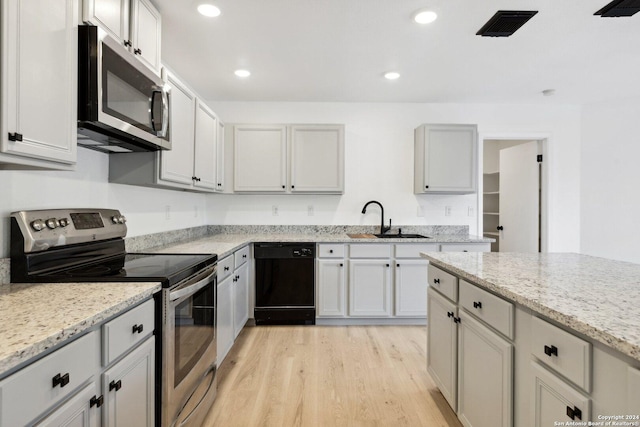 kitchen featuring light stone countertops, sink, light wood-type flooring, and stainless steel appliances