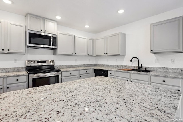 kitchen with light stone countertops, appliances with stainless steel finishes, gray cabinets, and sink