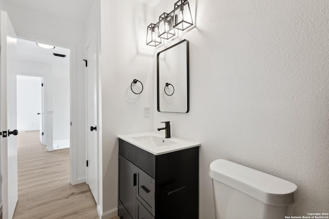 bathroom with toilet, vanity, and hardwood / wood-style flooring