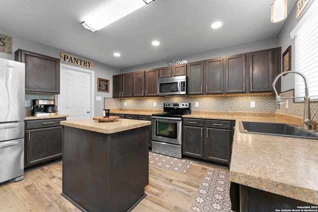 kitchen with a center island, sink, stainless steel appliances, and light hardwood / wood-style flooring