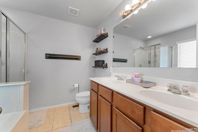 bathroom featuring tile patterned flooring, vanity, a shower with shower door, and toilet