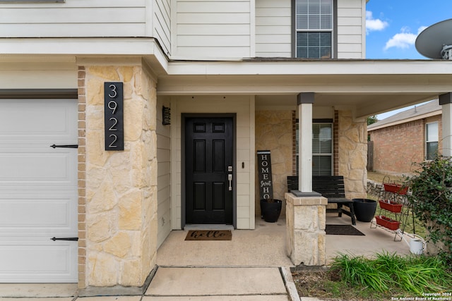 doorway to property with a porch and a garage