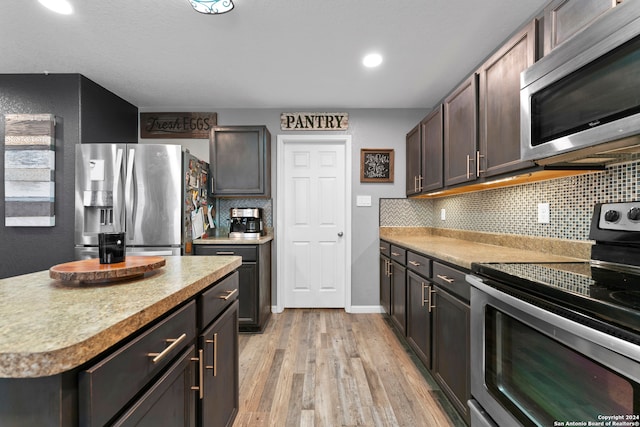 kitchen with dark brown cabinets, stainless steel appliances, light hardwood / wood-style flooring, and tasteful backsplash