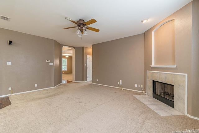 unfurnished living room featuring a tile fireplace, light carpet, and ceiling fan