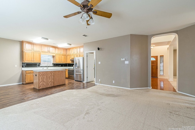 kitchen with appliances with stainless steel finishes, ceiling fan, sink, wood-type flooring, and a center island