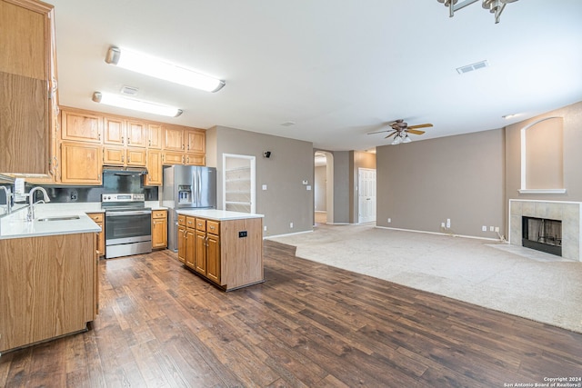 kitchen featuring dark wood-type flooring, sink, a fireplace, a kitchen island, and stainless steel appliances