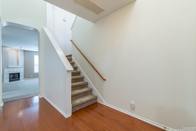 staircase with hardwood / wood-style flooring and a tile fireplace