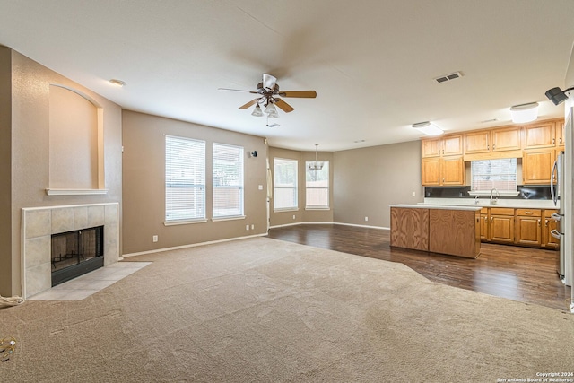 kitchen with ceiling fan, a center island, sink, light hardwood / wood-style flooring, and a fireplace