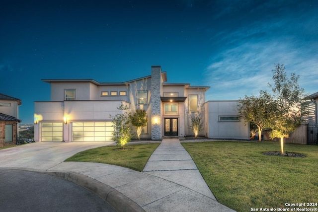 contemporary home featuring a yard, a garage, and french doors