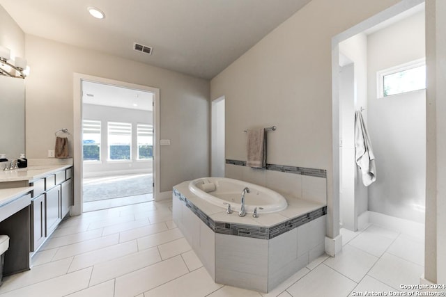 bathroom with tile patterned floors, vanity, and tiled tub