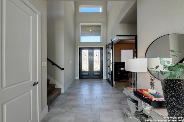 foyer entrance featuring french doors, a towering ceiling, and a barn door