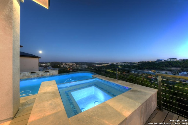 pool at dusk featuring an in ground hot tub