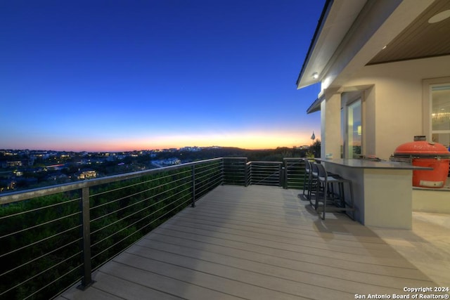 deck at dusk featuring area for grilling and exterior bar