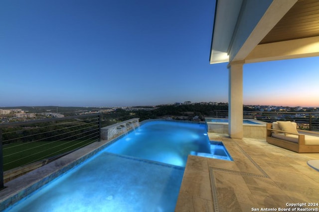 pool at dusk with pool water feature and a hot tub