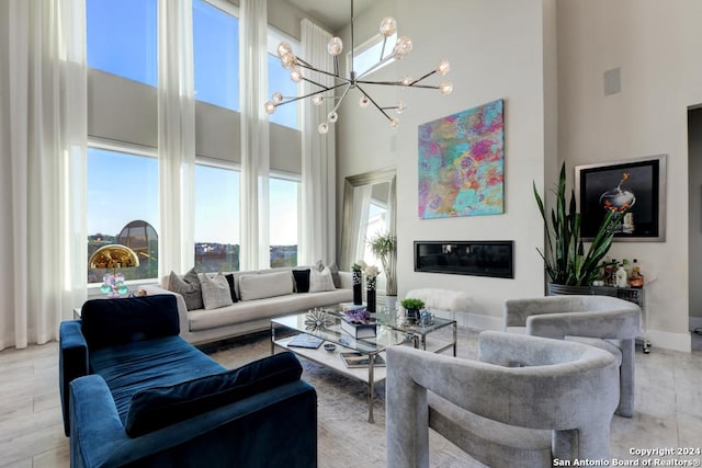 living room featuring a towering ceiling, a chandelier, and light hardwood / wood-style flooring